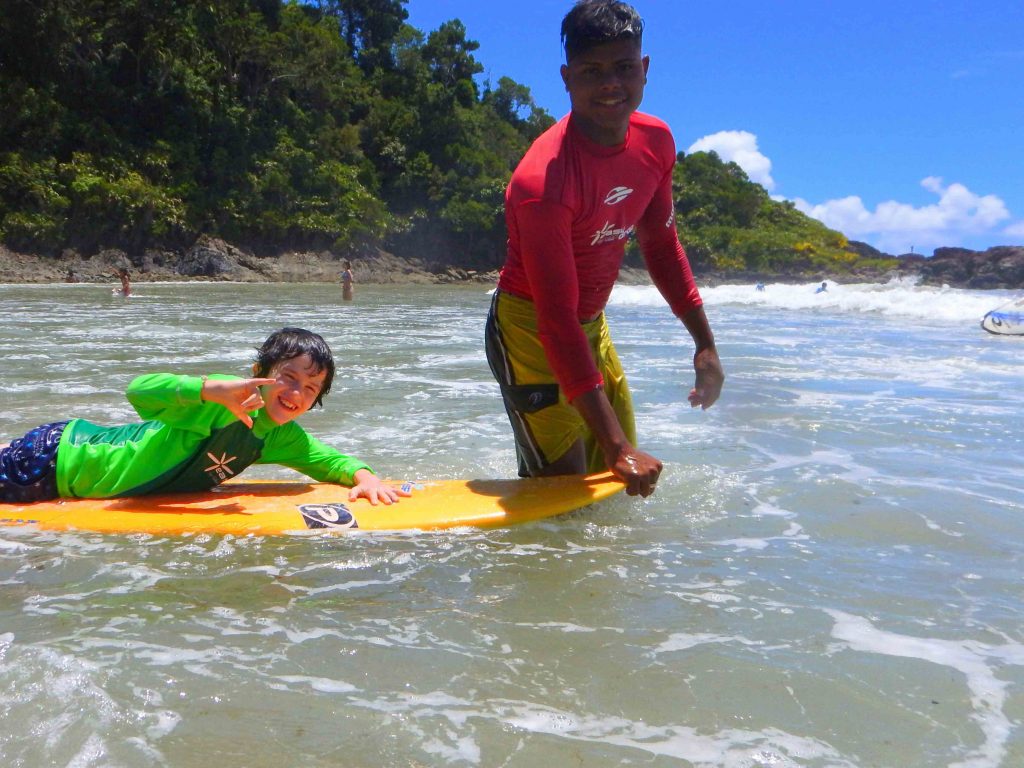 instrutor de surf com criança em longboard